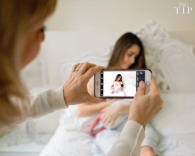 a woman taking a photo of herself on her cell phone while sitting in bed with another woman