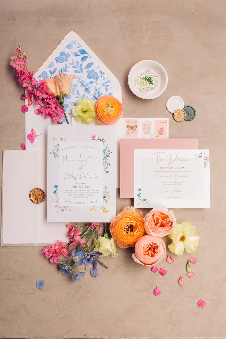 the wedding stationery is laid out with flowers