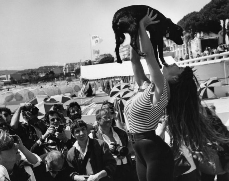 a woman holding up a cat above her head while people watch from the sidelines