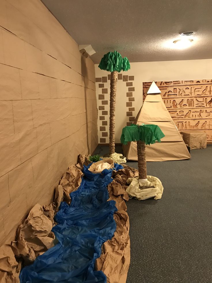 an indoor play area with fake trees and sandbags on the ground in front of it