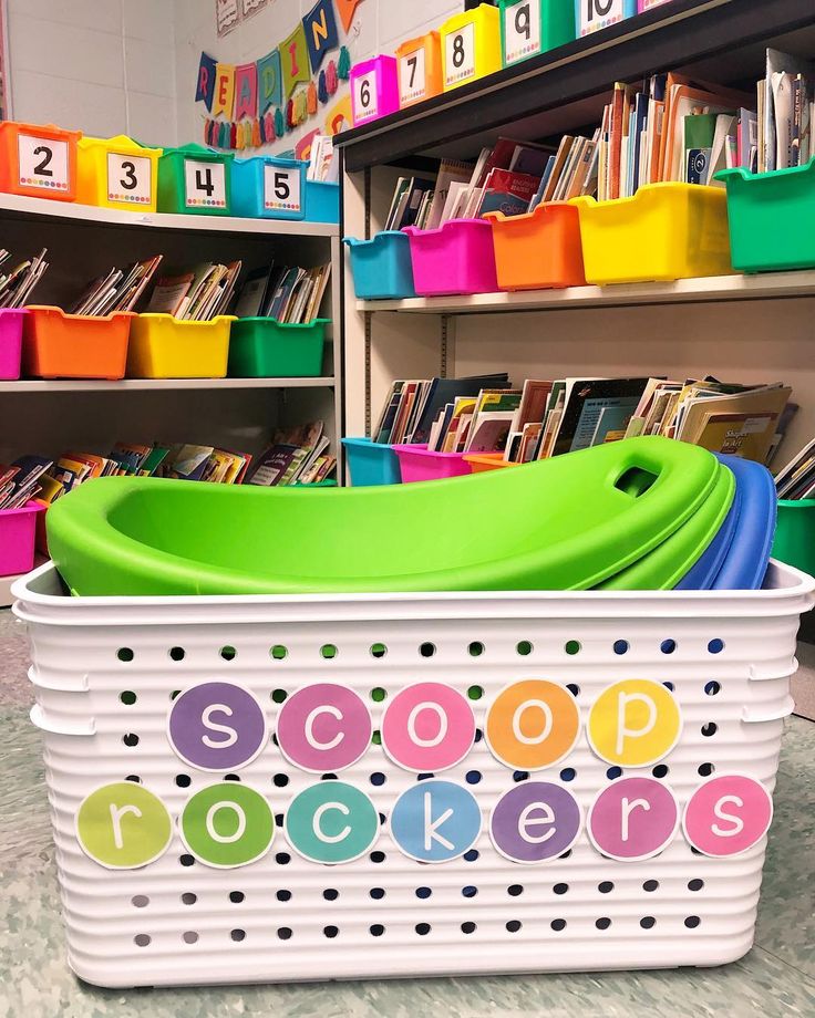 a white basket filled with lots of books on top of a floor next to a book shelf