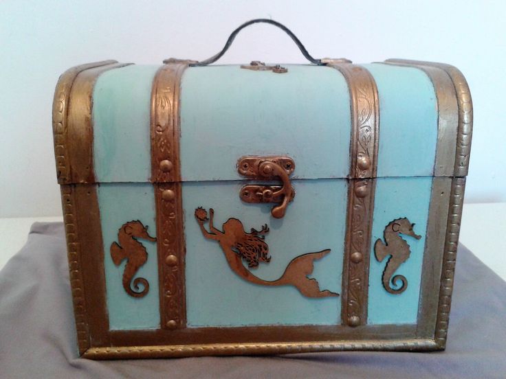 a blue and gold suitcase with seahorses painted on the side, sitting on top of a table