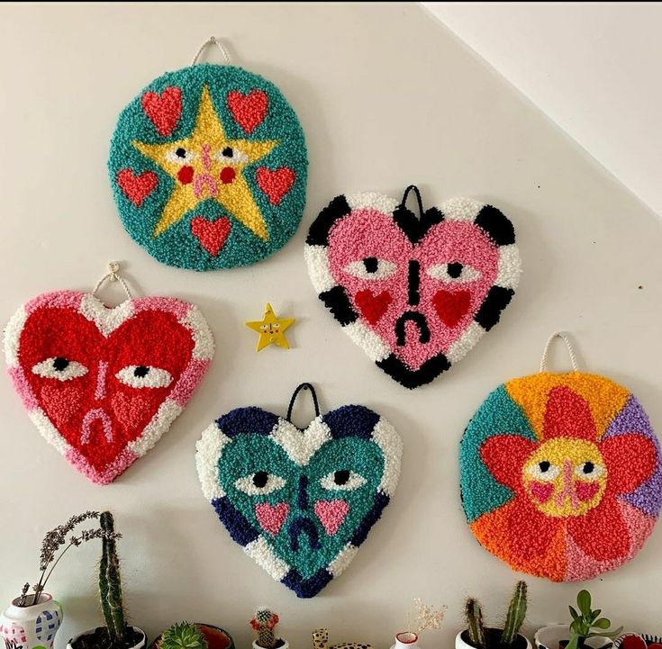 four heart shaped ornaments are hanging on the wall next to pots and cacti