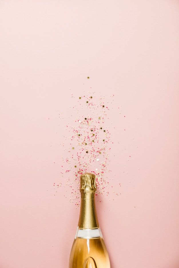 a bottle of champagne with sprinkles coming out of it on a pink background