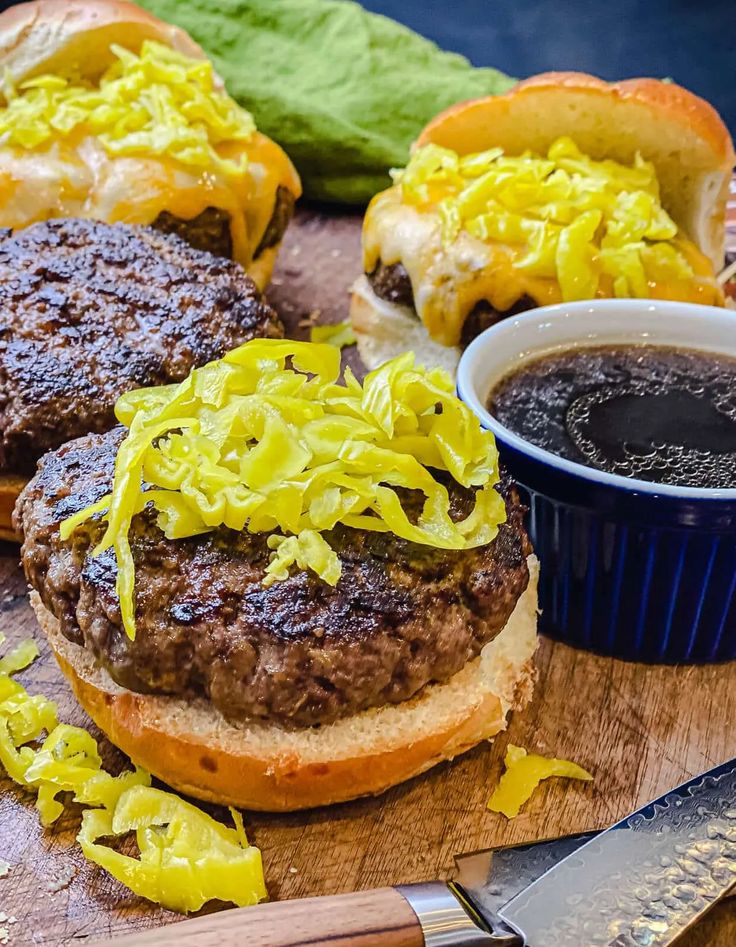 two hamburgers with lettuce and sauce on a cutting board