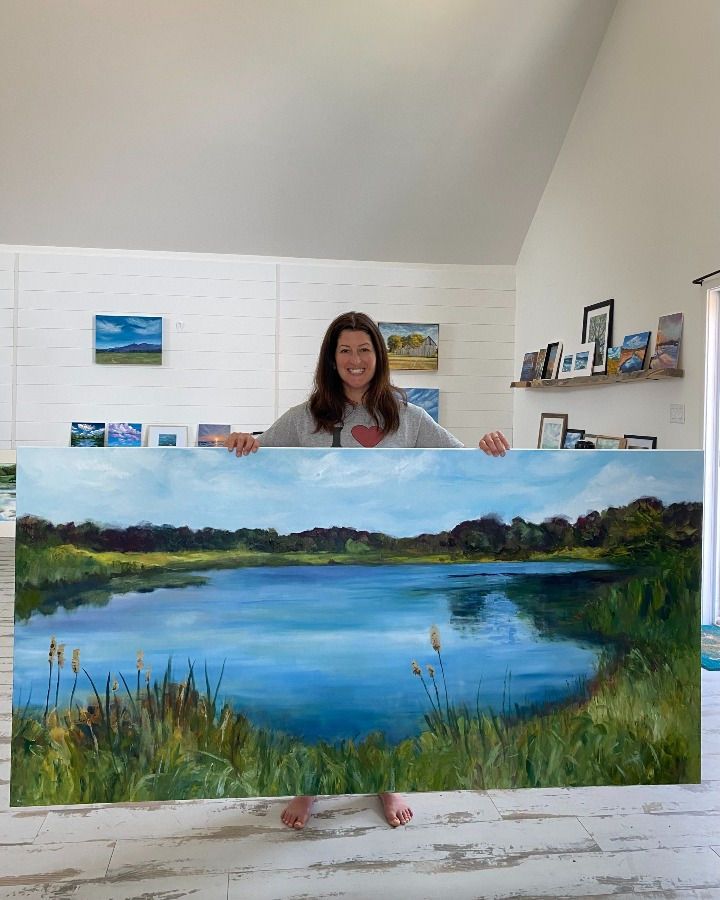 a woman holding up a painting in front of her