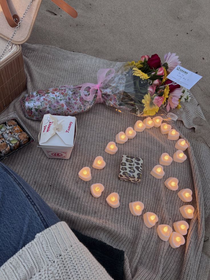 candles and flowers are laid out on the ground next to a box with a card in it