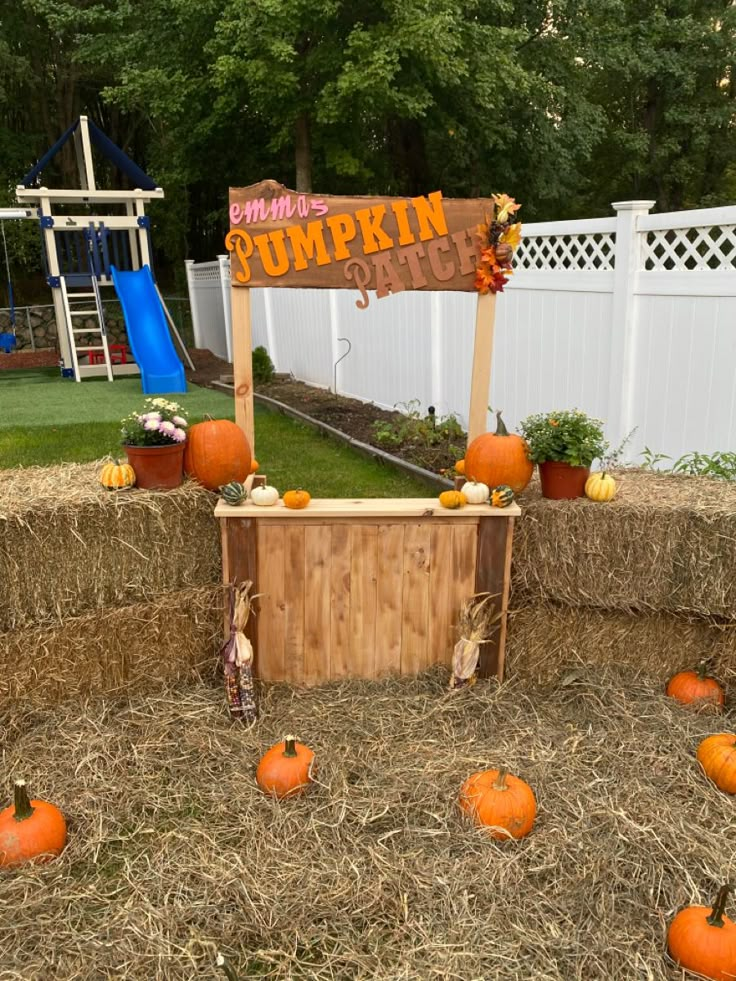 an outdoor pumpkin display with hay bales and fake pumpkins on the ground next to it