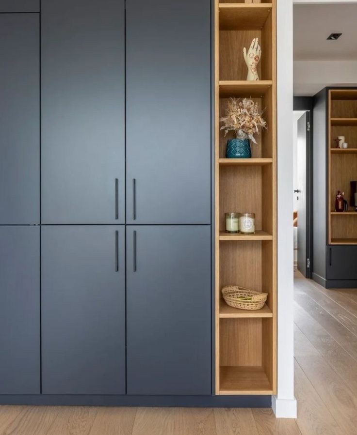 an open bookcase in the corner of a room with wooden floors and blue cabinets