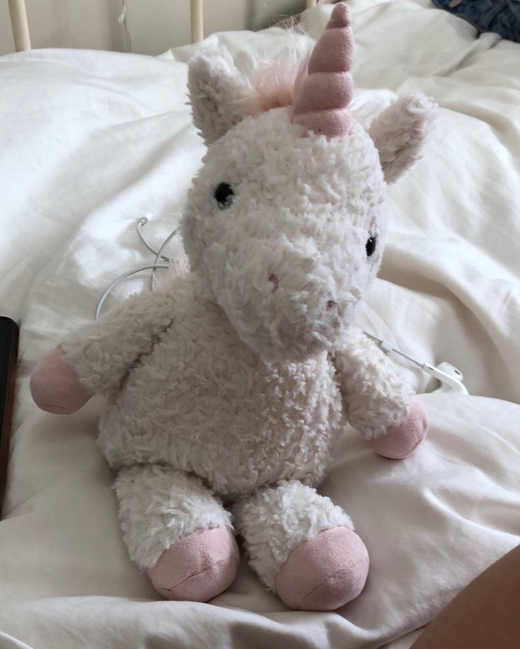 a white stuffed unicorn sitting on top of a bed