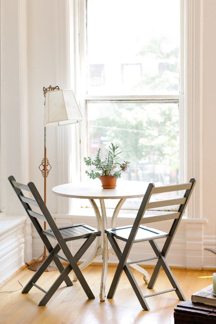 a white table and chairs in front of a window with a potted plant on it