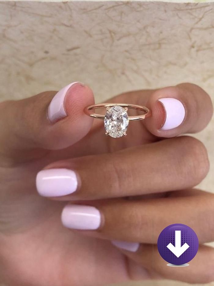 a woman's hand with pink and white manicured nails holding a diamond ring