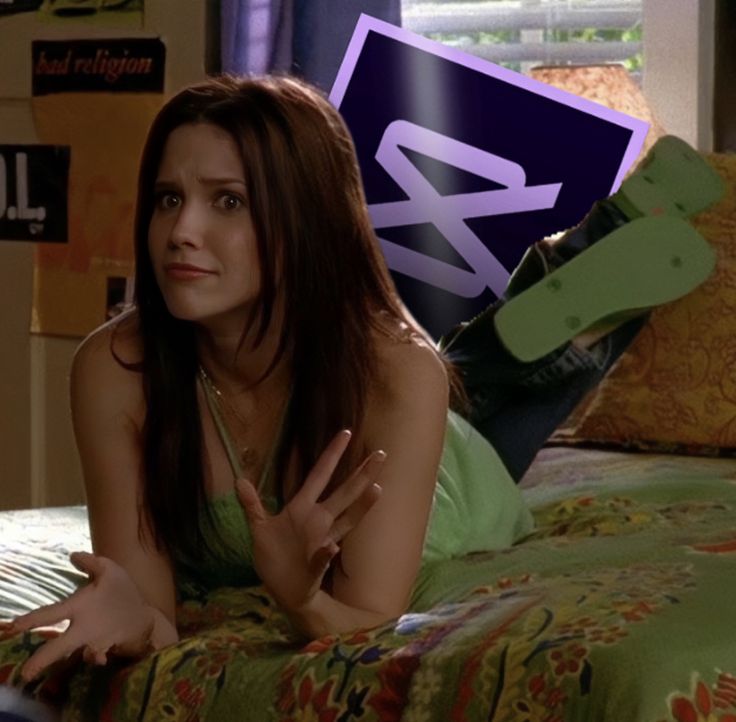 a woman laying on top of a bed next to a green pillow and a purple sign