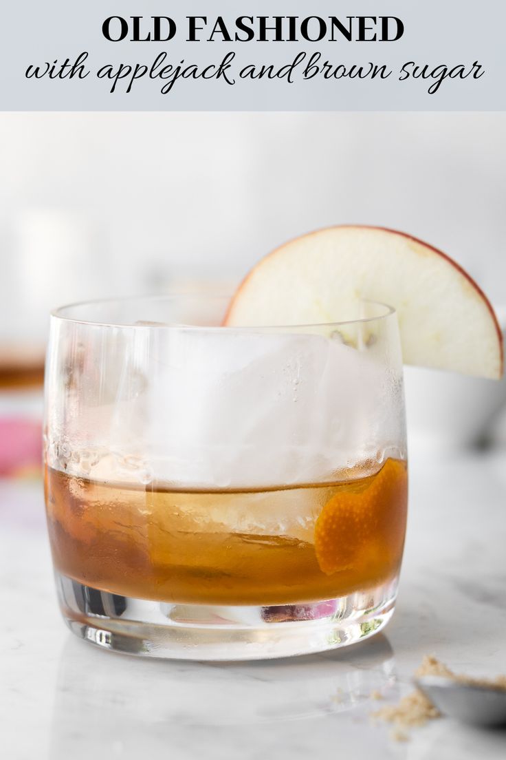 an apple sitting on top of a counter next to a glass filled with liquid and ice