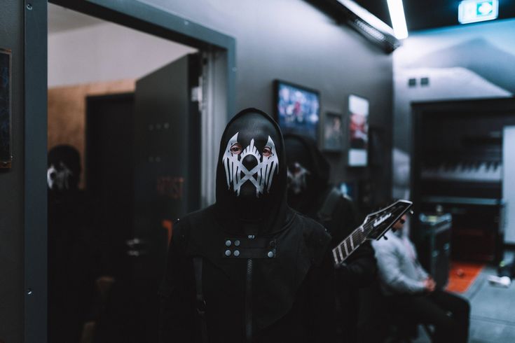 a person in a black hoodie with white paint on his face holding a guitar