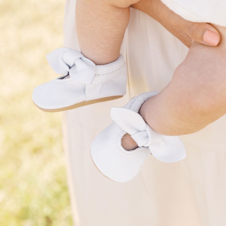 Step into pure elegance with our updated bright white mocc collection! Knotted Bow Mocc Bright White Leather Weathered Brown Leather Sole Choose between soft sole for your infant OR rubber hard sole for your little on the go Soft soles come in sizes Newborn - 7 Hard soles come in sizes 3 - 7 White Non-slip Booties With Round Toe, Cute Spring Booties With Soft Sole, Spring Booties With Soft Sole And Round Toe, White Moccasins With Rubber Sole For Spring, White Booties With Rubber Sole For Playtime, White Slip-on Moccasins For Summer, Cute White Slip-on Booties, White Closed Toe Moccasins With Rubber Sole, White Slip-on Cute Booties