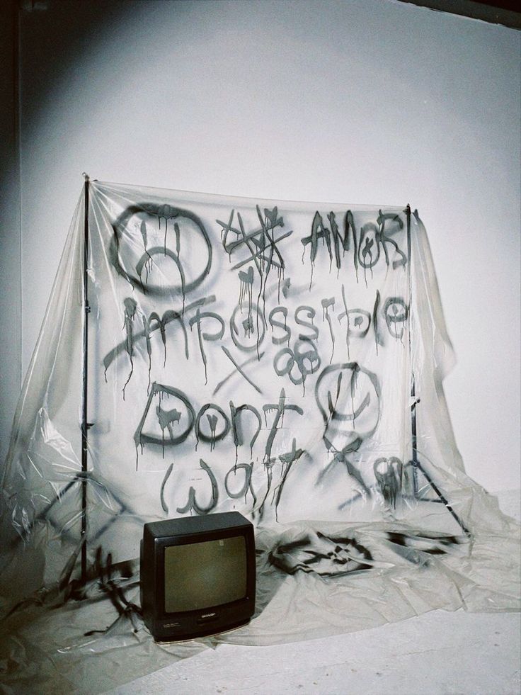 a tv sitting on top of a white sheet covered floor next to a graffiti covered wall