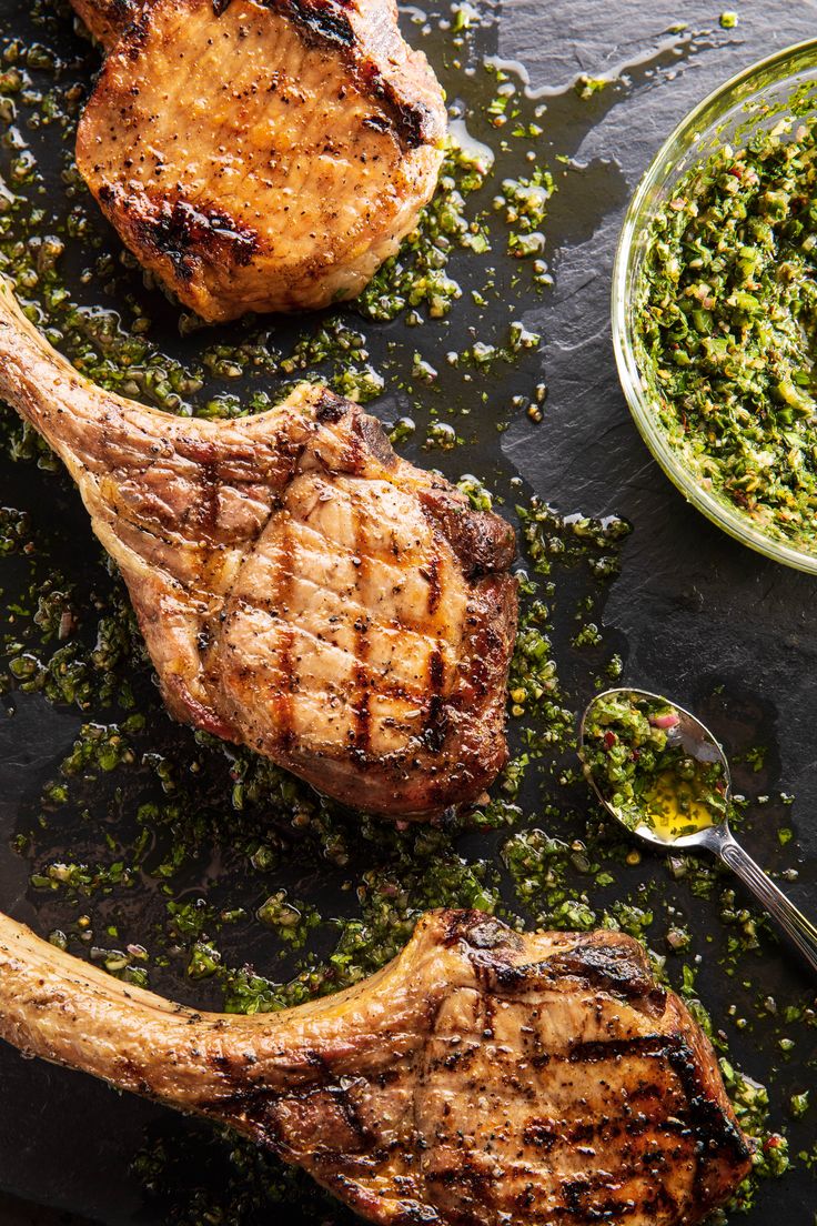 grilled steaks with chimica pest on a black slate platter next to a glass bowl