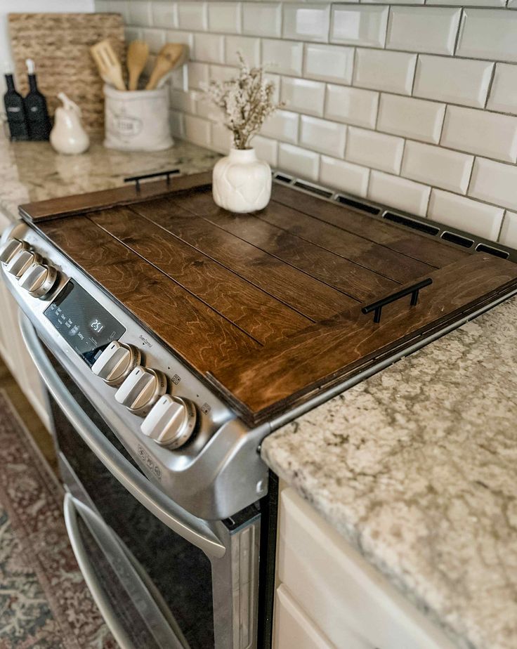 a stove top oven sitting inside of a kitchen next to a counter with a wooden cutting board on it