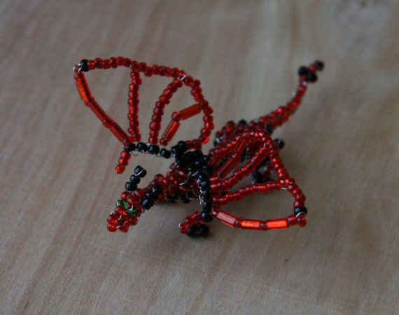 a red beaded brooch sitting on top of a wooden table