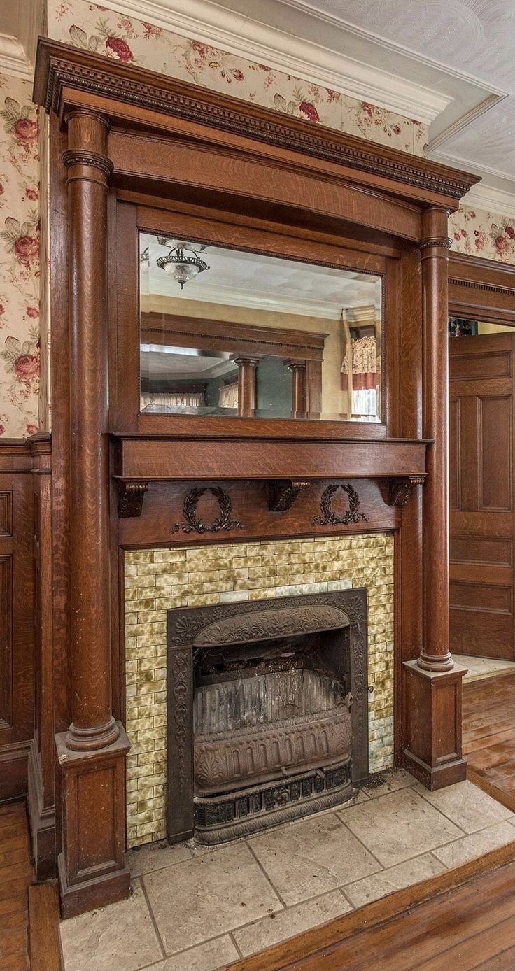 a fireplace with a mirror above it in a room that has wood paneling and floral wallpaper on the walls