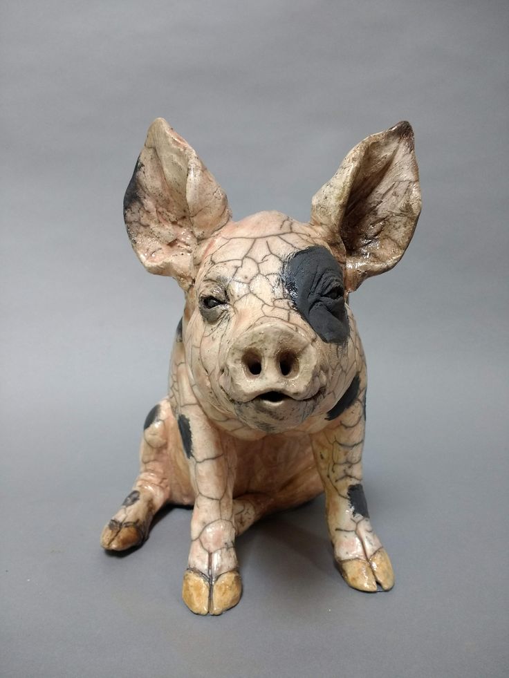 a ceramic pig sitting on top of a gray surface