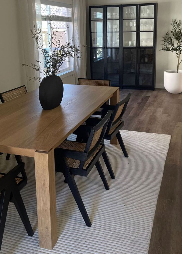 a dining room table with chairs and a vase on it