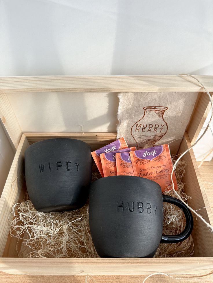 two black mugs sitting in a wooden box