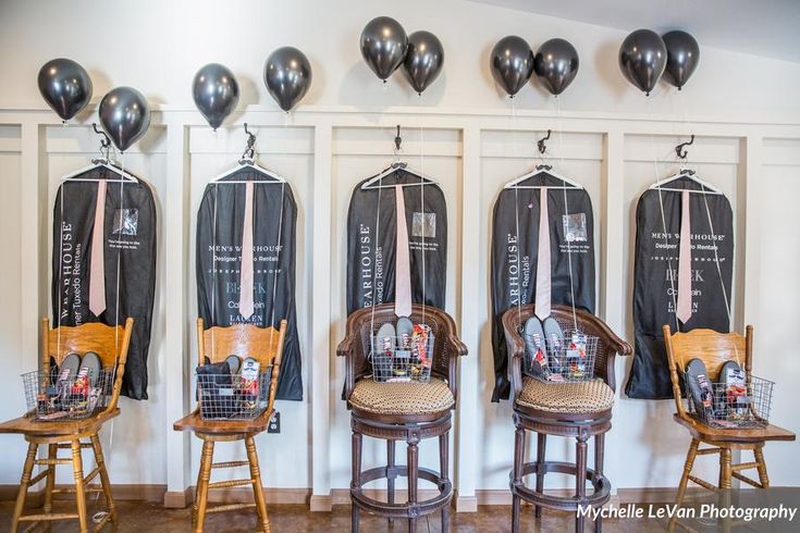 several chairs and stools are lined up against the wall with black balloons hanging above them