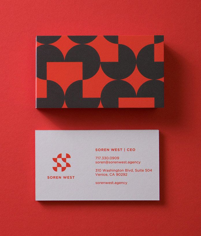 two business cards sitting side by side on a red surface with black and white designs