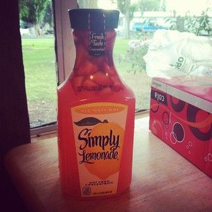 a bottle of lemonade sitting on top of a wooden table next to a window