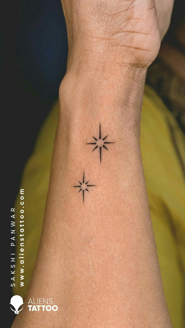 a person with a small tattoo on their wrist that has three stars in the middle