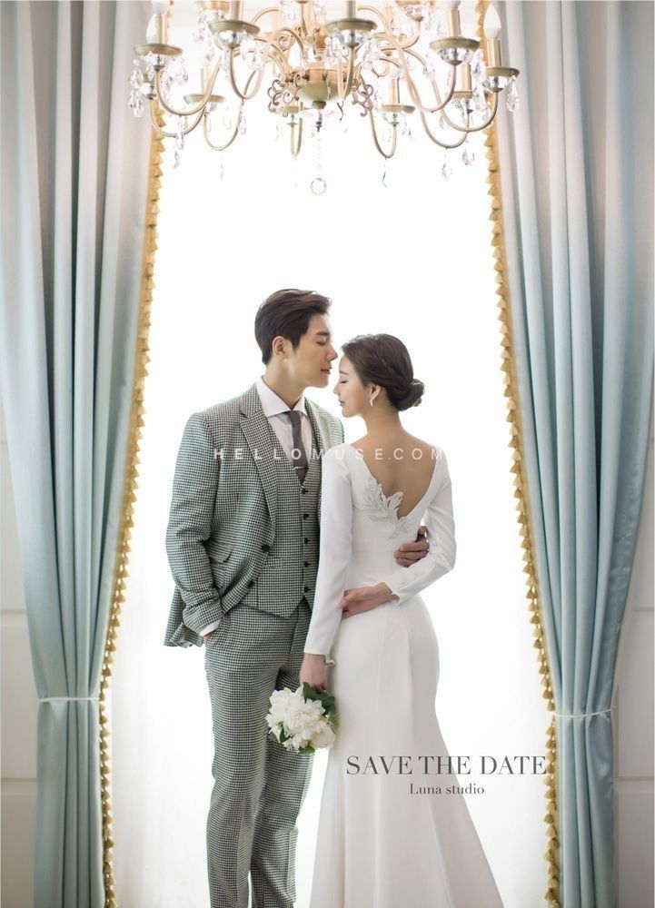 a bride and groom standing next to each other in front of a chandelier