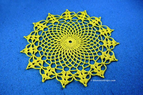 a crocheted doily is shown on a blue surface