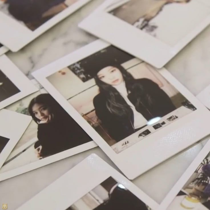 many polaroid photos are arranged on the table top, with one woman's face visible