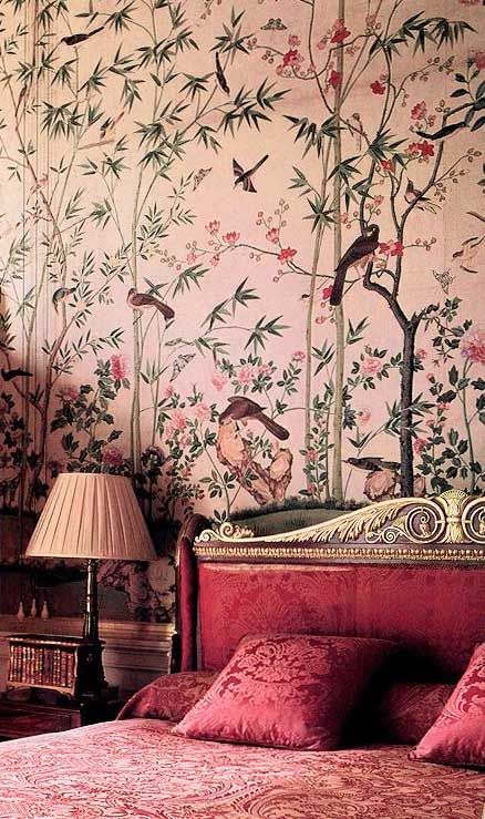 a bedroom with pink and green wallpaper, red bedspread, two lamps on either side of the bed