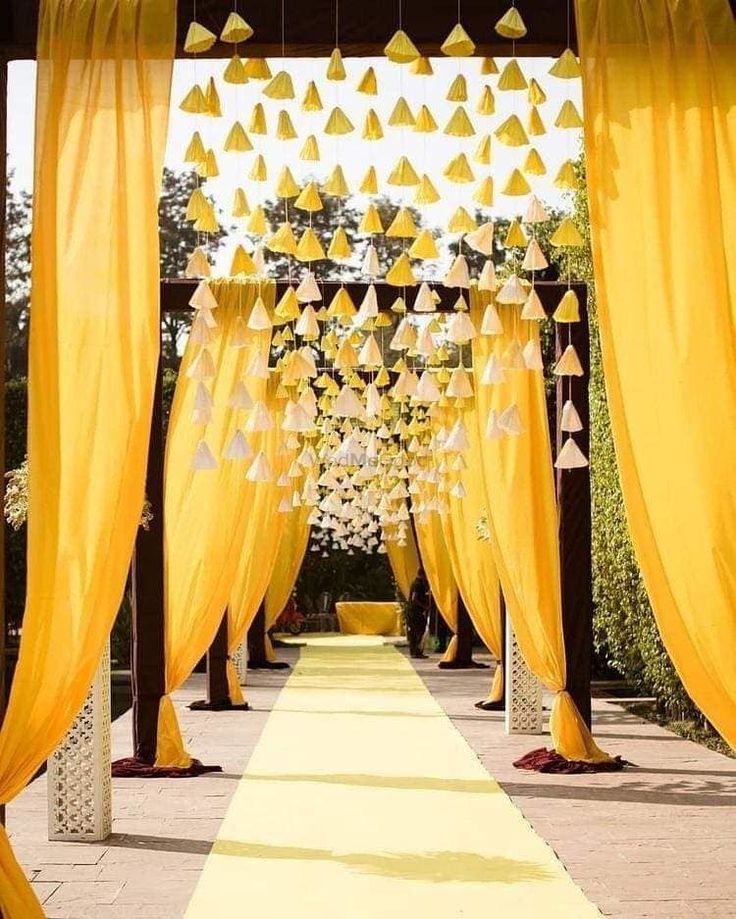 an outdoor ceremony with yellow drapes and decorations