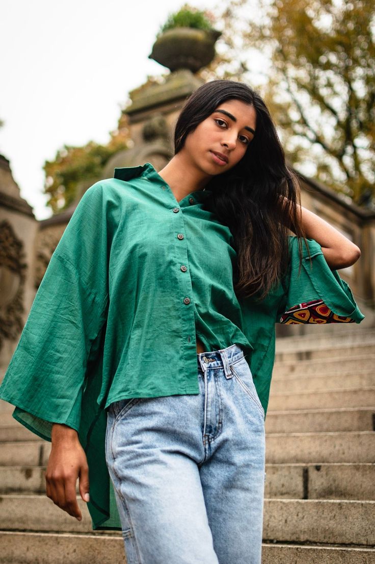 Oversized high-low shirt with dropped shoulders in teal green with wooden buttons and subtle bell sleeves. Elbow patch embellished with preloved Kutchi hand embroidery by the artisan of Kutch, Gujarat. Note: Embroidery patch (color and design) vary in each piece Handcrafted in India Green Tunic Blouse For Fall, Green Tunic Top For Fall, Oversized Cotton Bohemian Blouse, Bohemian Cotton Tops With Bell Sleeves, Bohemian Cotton Top With Bell Sleeves, Bohemian Bell Sleeve Cotton Top, Oversized Green Cotton Blouse, Dark Green Cotton Tops For Spring, Dark Green Cotton Top For Spring