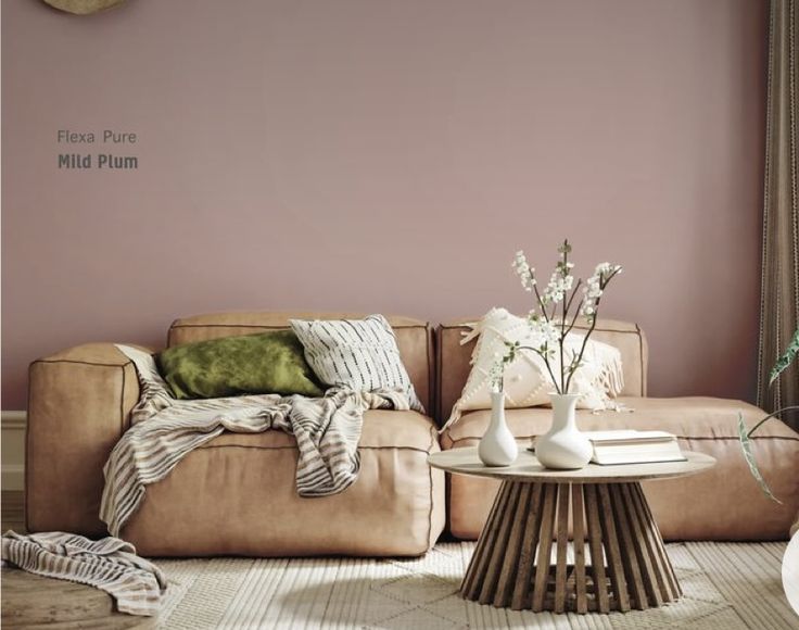 a living room filled with furniture and flowers on top of a coffee table in front of a pink wall