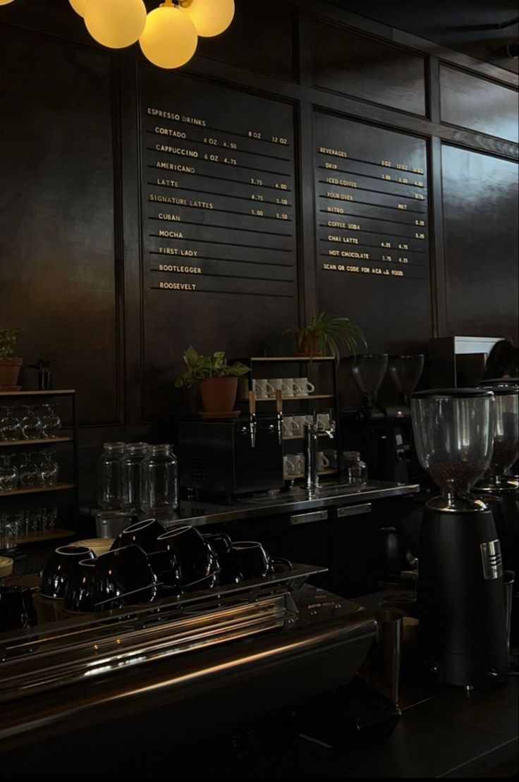 a coffee shop with many cups on the counter and lights hanging from the ceiling above