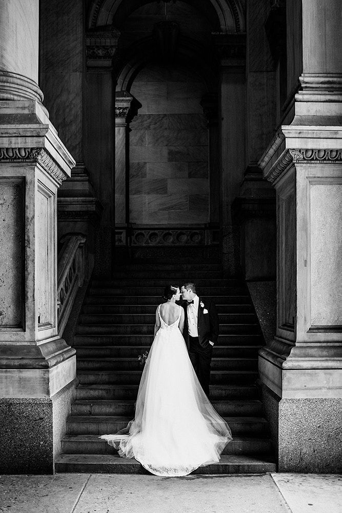 a bride and groom are standing on the stairs in front of an ornate building with columns