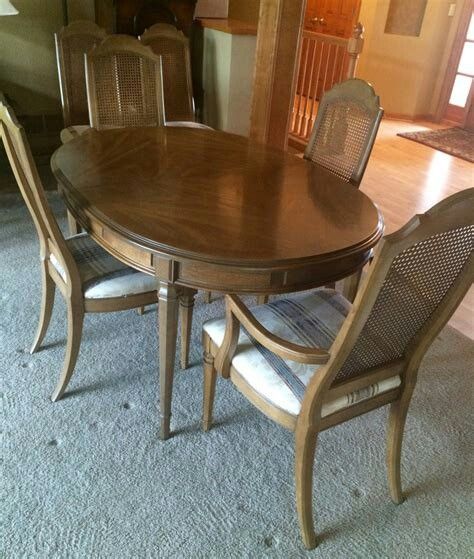 a dining room table with four chairs and a rug on the floor in front of it