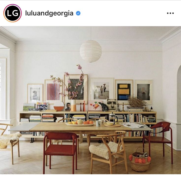 a dining room table surrounded by bookshelves and pictures on the wall behind it