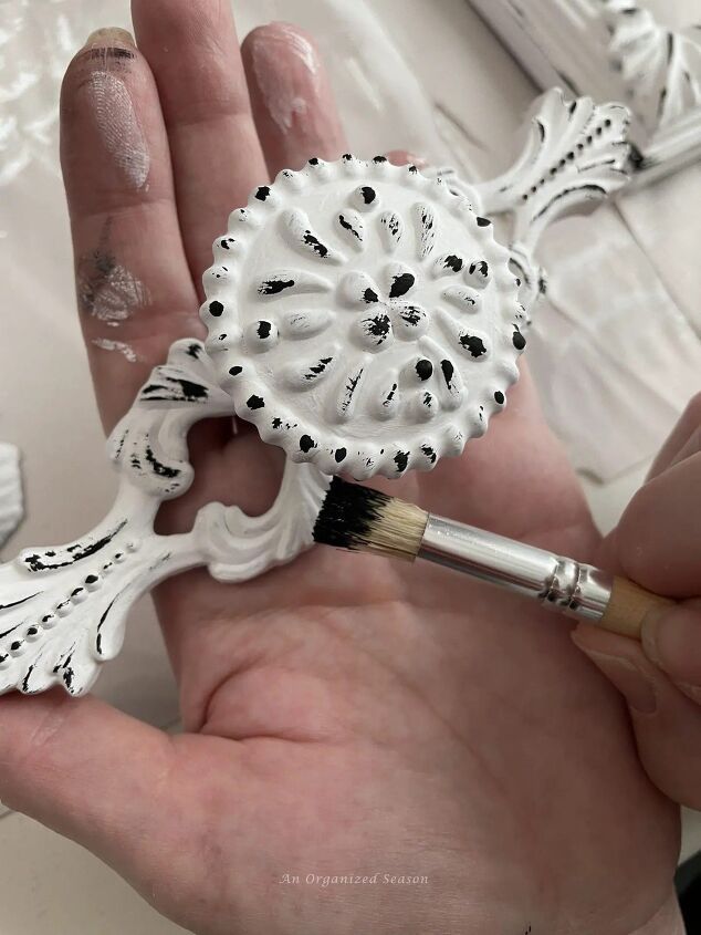 a person holding a paintbrush in their hand next to a white flower shaped object