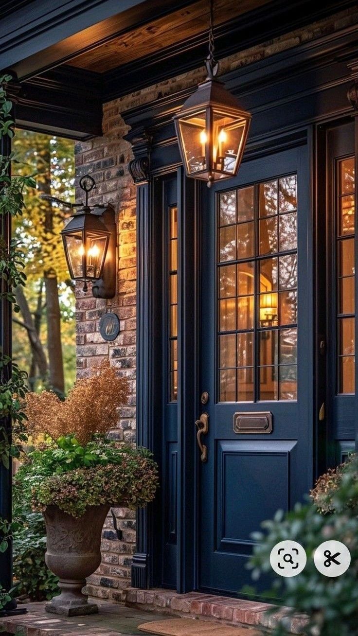 a blue front door with two lights on it and a potted plant in the foreground