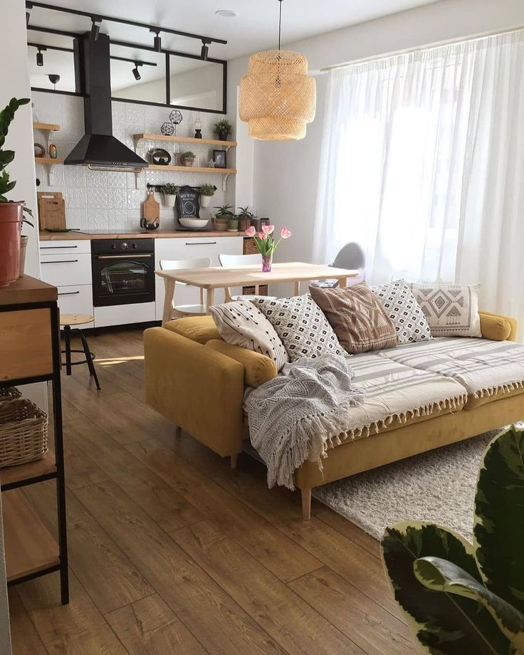 a living room filled with furniture next to a kitchen and dining room table on top of a hard wood floor