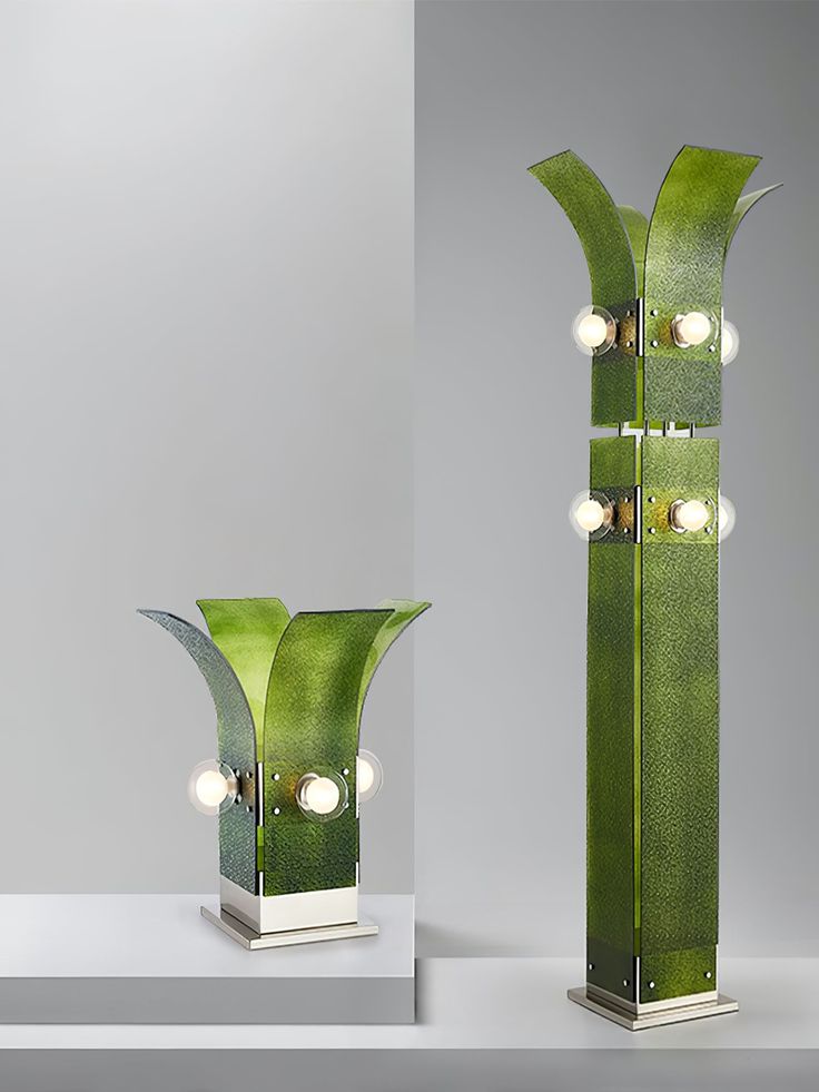 a tall green vase sitting on top of a white table next to a light fixture