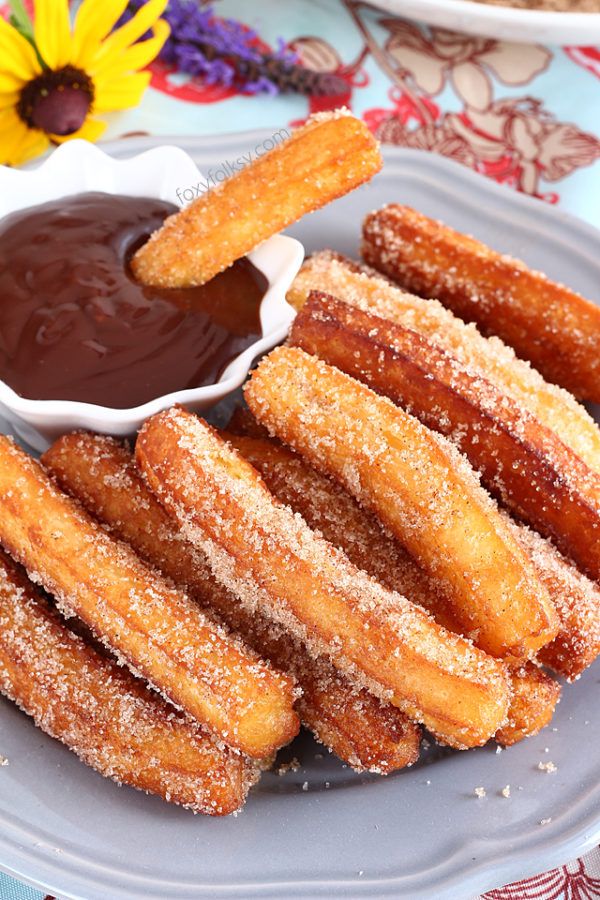 churros on a plate with dipping sauce and flowers in the backgroud