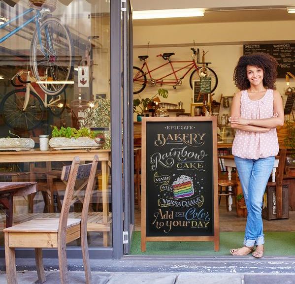 a woman standing in front of a bakery with her arms crossed