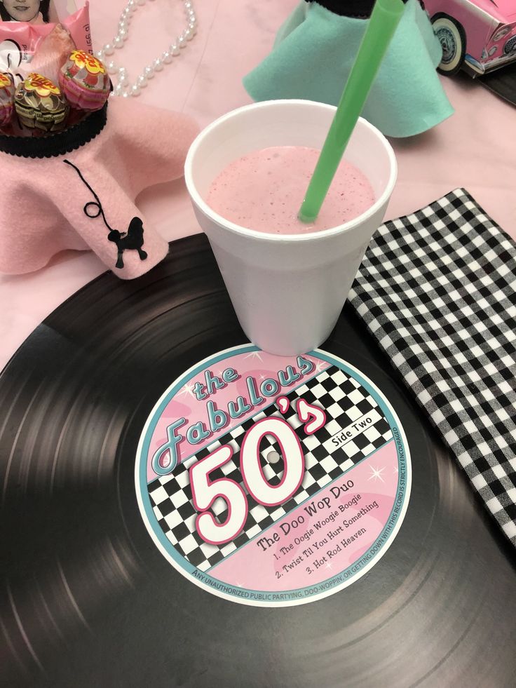 a pink drink in a plastic cup on top of a record